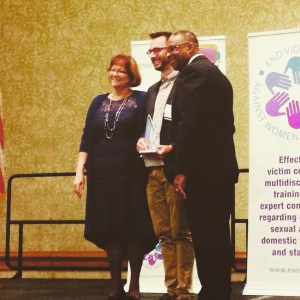 John Sutter receiving his media and journalism award from Joanne Archembault and Herman Milhollend at the EVAWI conference 2015. 